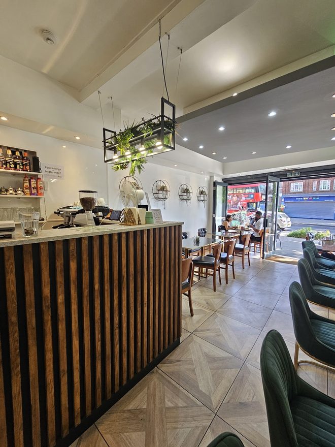 The slatted wooden coffee counter and espresso machine seen across the empty room toward the front windows