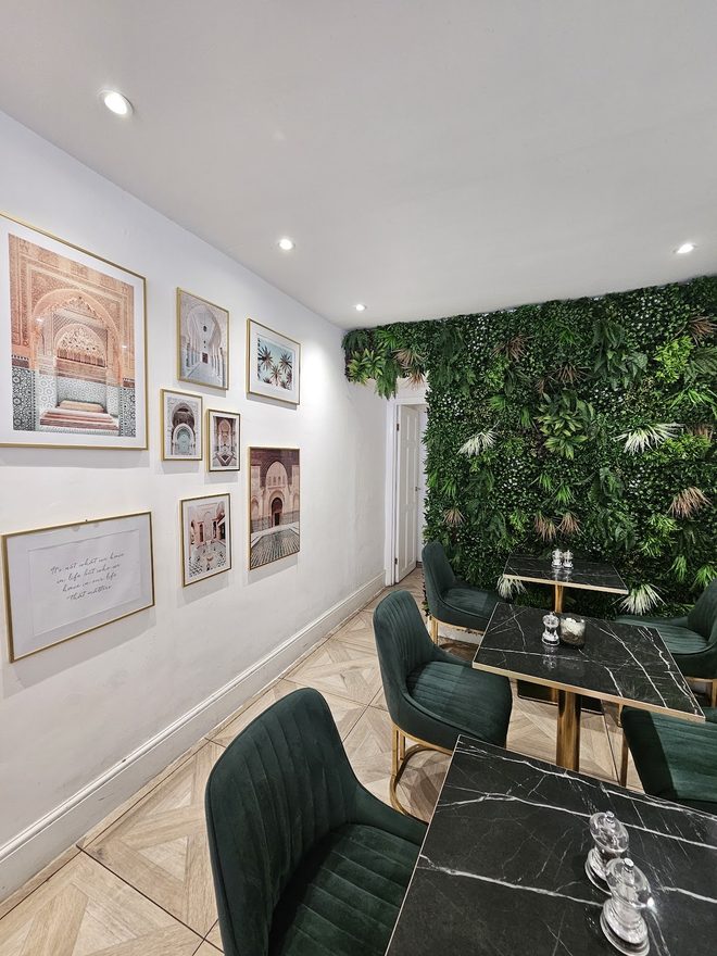 Quiet corner of the dining room with a framed picture gallery wall, a living plant wall and green chairs