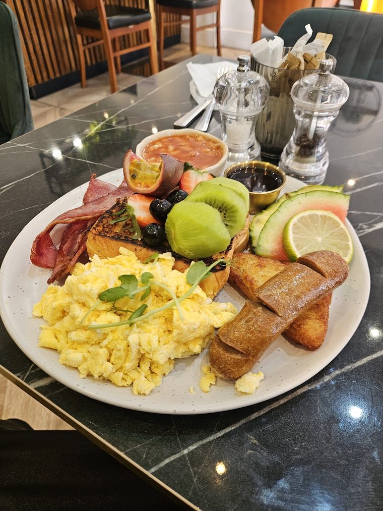 Full breakfast plate with scrambled eggs, bacon, fried potatoes, avocado and tomato