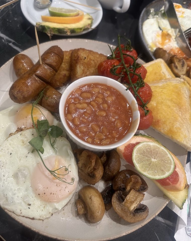 Breakfast platter with sausages, baked beans, fried egg, mushrooms, halloumi and fresh fruit